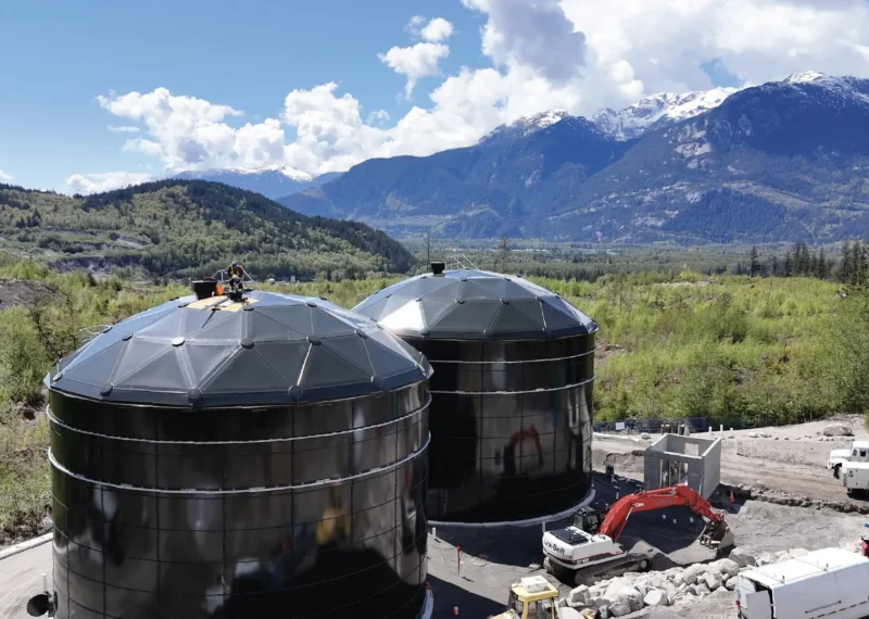 Two forest green water storage tanks built by Greatario with a mountain background in Squamish, British Columbia