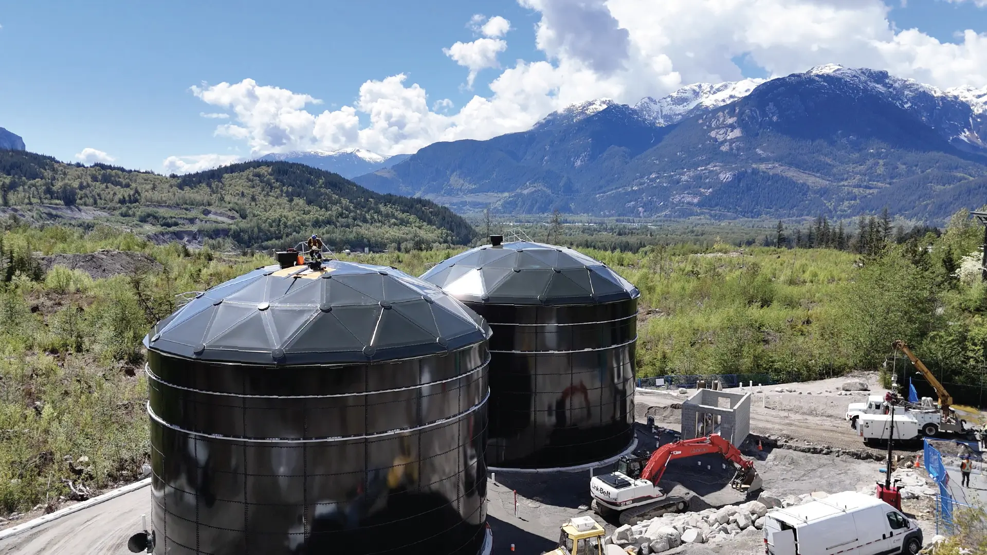 Two forest green water storage tanks built by Greatario with a mountain background in Squamish, British Columbia