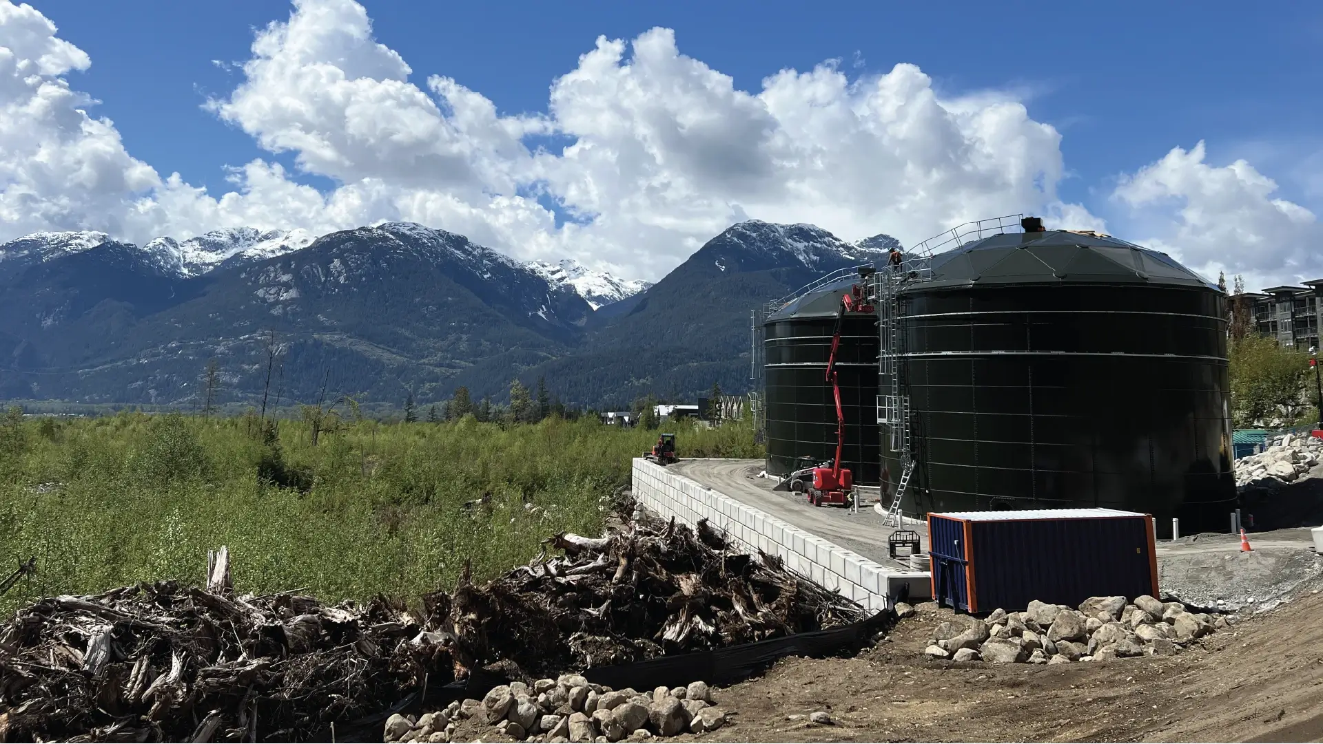 Two forest green water storage tanks built by Greatario with a mountain background in Squamish, British Columbia