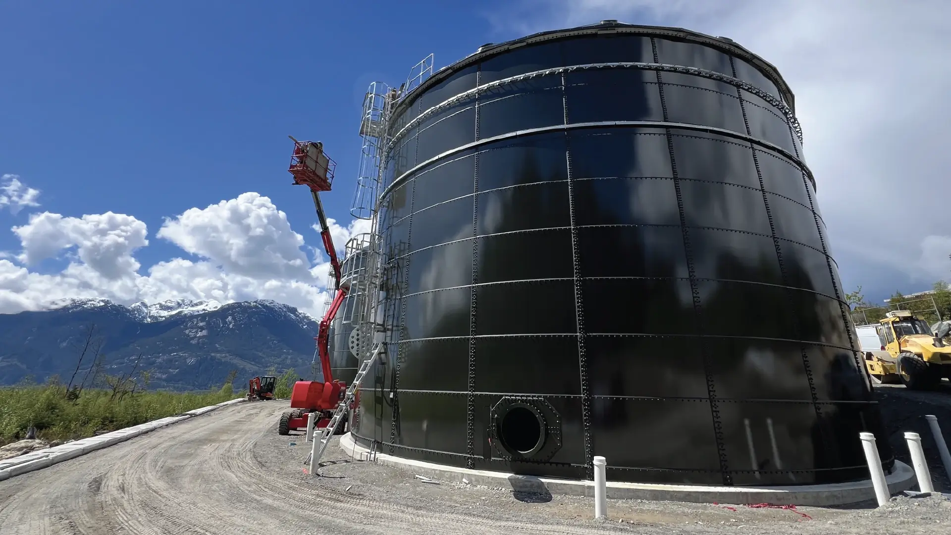 A forest green water storage tank built by Greatario with a blue sky background in Squamish, British Columbia